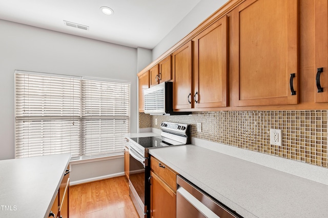 kitchen featuring plenty of natural light, light hardwood / wood-style floors, decorative backsplash, and stainless steel appliances