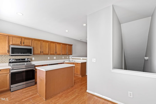 kitchen with sink, stainless steel appliances, tasteful backsplash, light hardwood / wood-style flooring, and a kitchen island