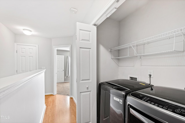 clothes washing area featuring washer and clothes dryer and light hardwood / wood-style flooring