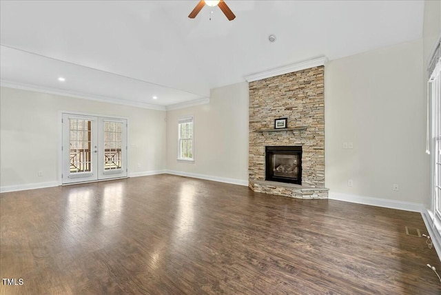 unfurnished living room with dark wood-type flooring, french doors, a fireplace, ceiling fan, and crown molding