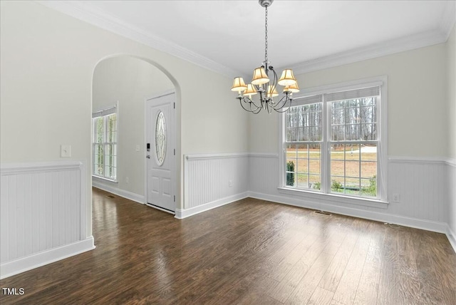 empty room with dark hardwood / wood-style flooring, ornamental molding, and a healthy amount of sunlight