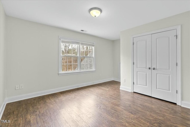 unfurnished bedroom featuring a closet and dark hardwood / wood-style flooring