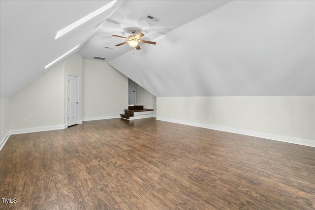 bonus room with ceiling fan, vaulted ceiling with skylight, and dark hardwood / wood-style floors