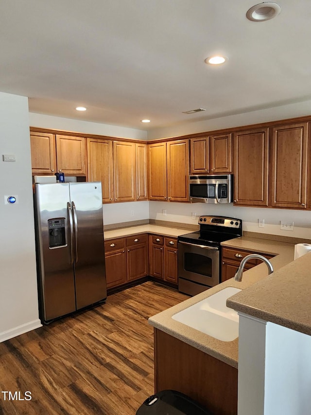 kitchen featuring kitchen peninsula, stainless steel appliances, dark hardwood / wood-style floors, and sink