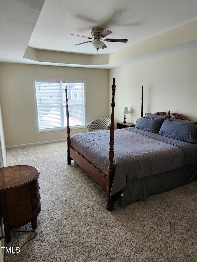 bedroom featuring light colored carpet, ceiling fan, and a tray ceiling