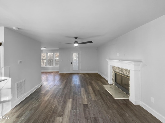 unfurnished living room featuring a fireplace, ceiling fan, and dark wood-type flooring