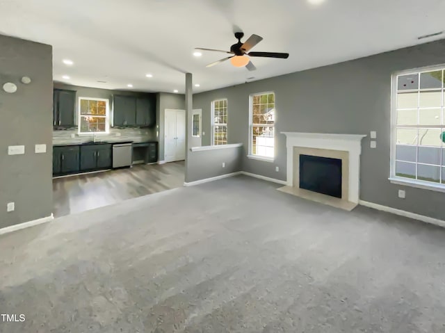 unfurnished living room featuring ceiling fan and sink