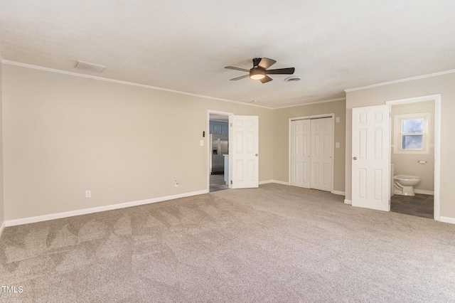 unfurnished bedroom featuring ceiling fan, carpet floors, ensuite bathroom, and ornamental molding