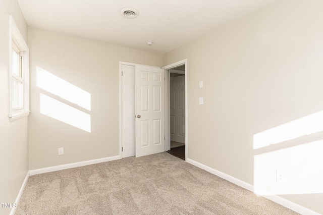 unfurnished bedroom featuring light colored carpet and multiple windows