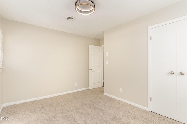 unfurnished bedroom featuring light colored carpet and a closet