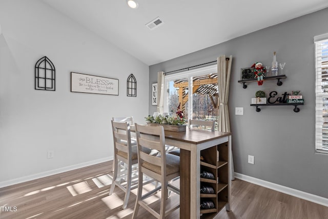 dining space with vaulted ceiling and hardwood / wood-style flooring