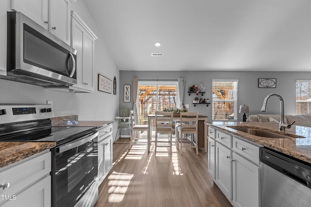 kitchen featuring appliances with stainless steel finishes, white cabinetry, plenty of natural light, and sink