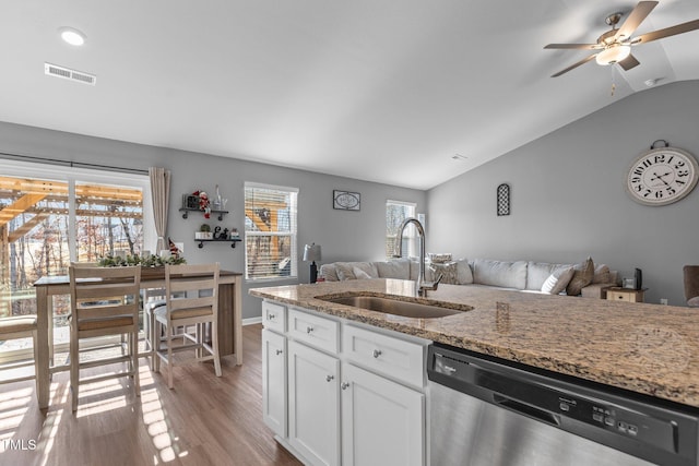 kitchen with lofted ceiling, sink, stainless steel dishwasher, a healthy amount of sunlight, and light stone counters