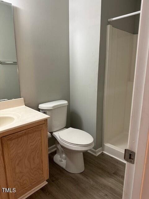 bathroom with hardwood / wood-style floors, vanity, toilet, and walk in shower