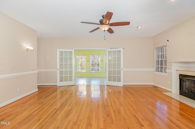 unfurnished living room with french doors, ceiling fan, and light hardwood / wood-style flooring