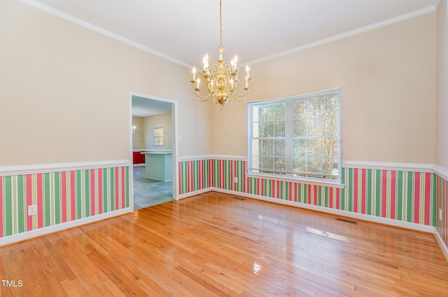 empty room featuring crown molding, hardwood / wood-style floors, and a chandelier