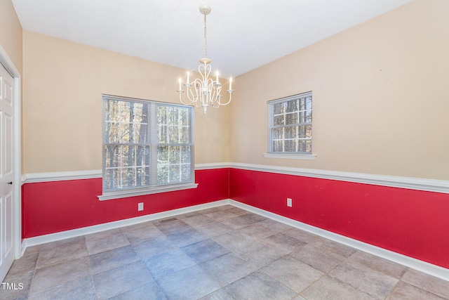 unfurnished room with a notable chandelier