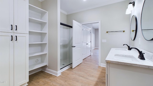 bathroom with double vanity, a sink, baseboards, and wood finished floors