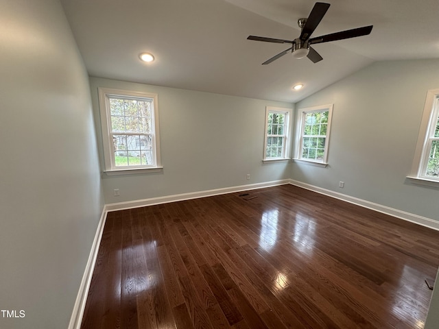 spare room with dark hardwood / wood-style flooring, a wealth of natural light, and vaulted ceiling