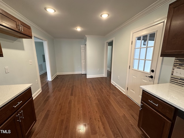 kitchen with light stone counters, dark brown cabinetry, ornamental molding, and dark hardwood / wood-style flooring