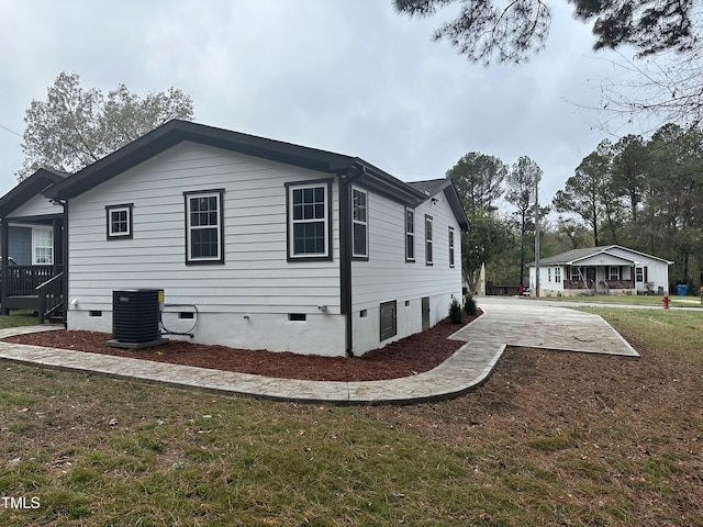 view of side of property featuring central AC unit and a lawn