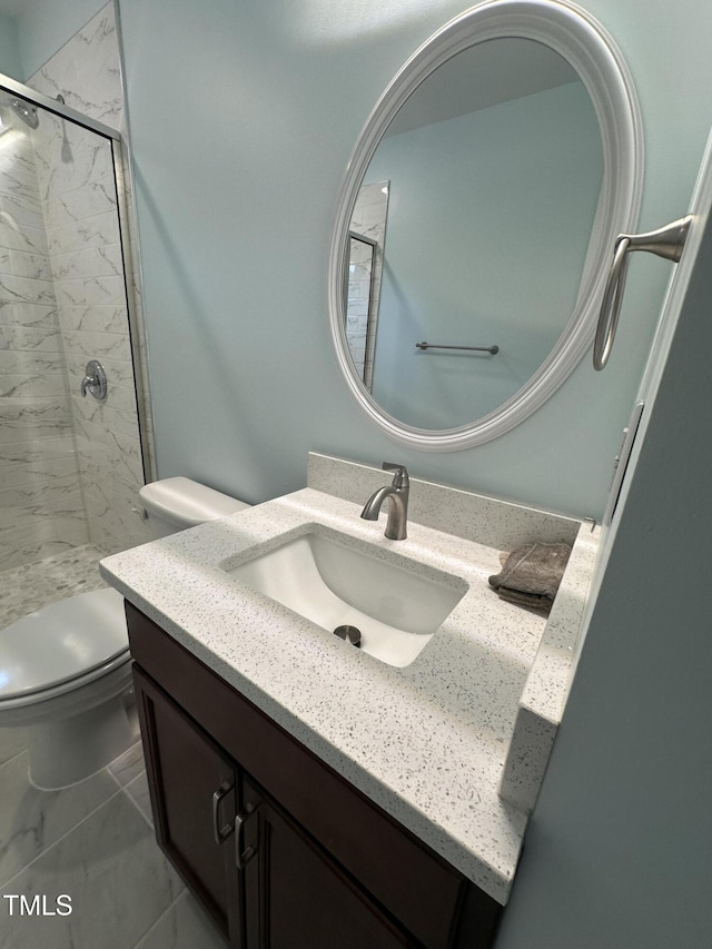 bathroom with vanity, tile patterned floors, toilet, and tiled shower