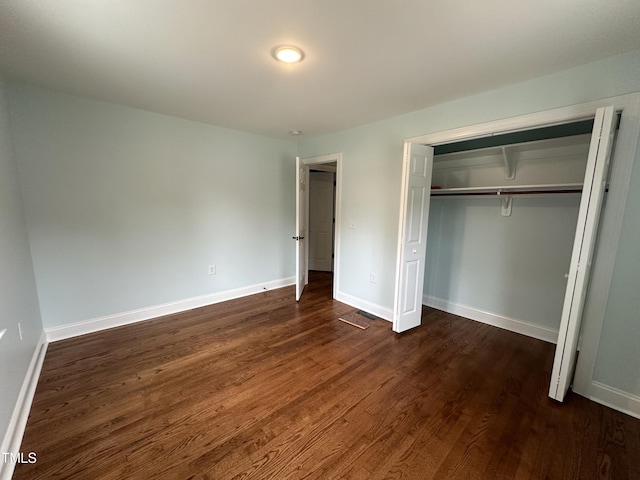 unfurnished bedroom featuring dark hardwood / wood-style flooring and a closet