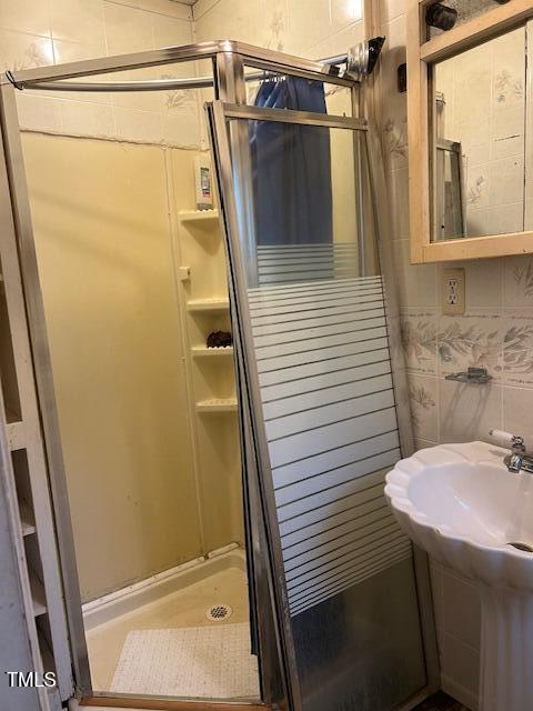 bathroom featuring an enclosed shower and tile walls