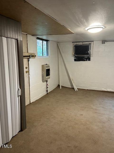 basement with a textured ceiling and heating unit