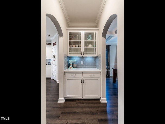 bar featuring decorative backsplash, crown molding, white cabinetry, and dark wood-type flooring