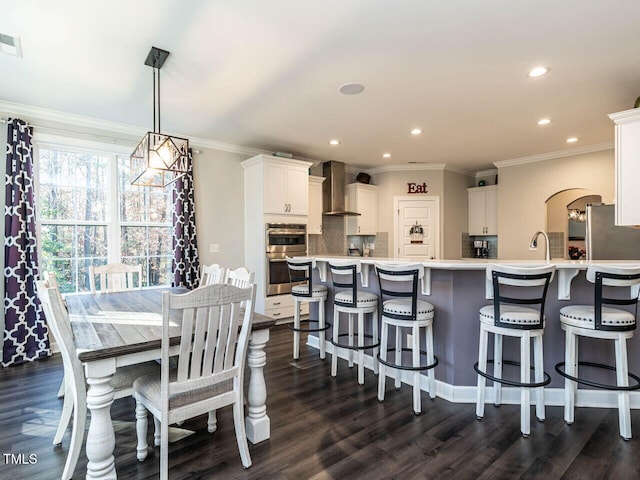 kitchen with tasteful backsplash, white cabinetry, wall chimney exhaust hood, and dark wood-type flooring