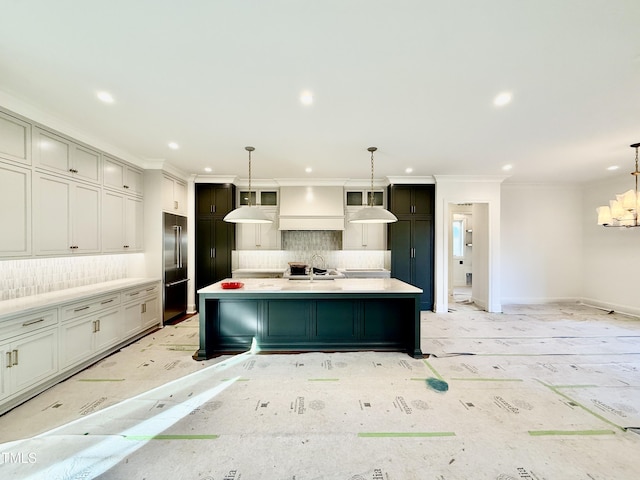 kitchen with decorative backsplash, pendant lighting, high quality fridge, a spacious island, and sink