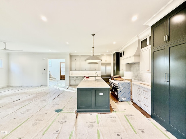 kitchen featuring an island with sink, ornamental molding, white cabinets, and pendant lighting