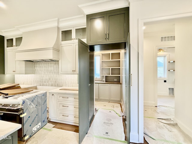 kitchen featuring white cabinetry, decorative backsplash, crown molding, and custom range hood