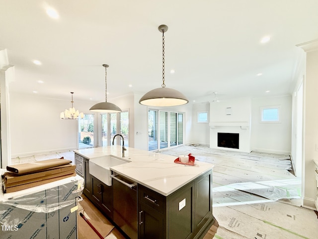 kitchen featuring an island with sink, light wood-type flooring, hanging light fixtures, sink, and stainless steel dishwasher