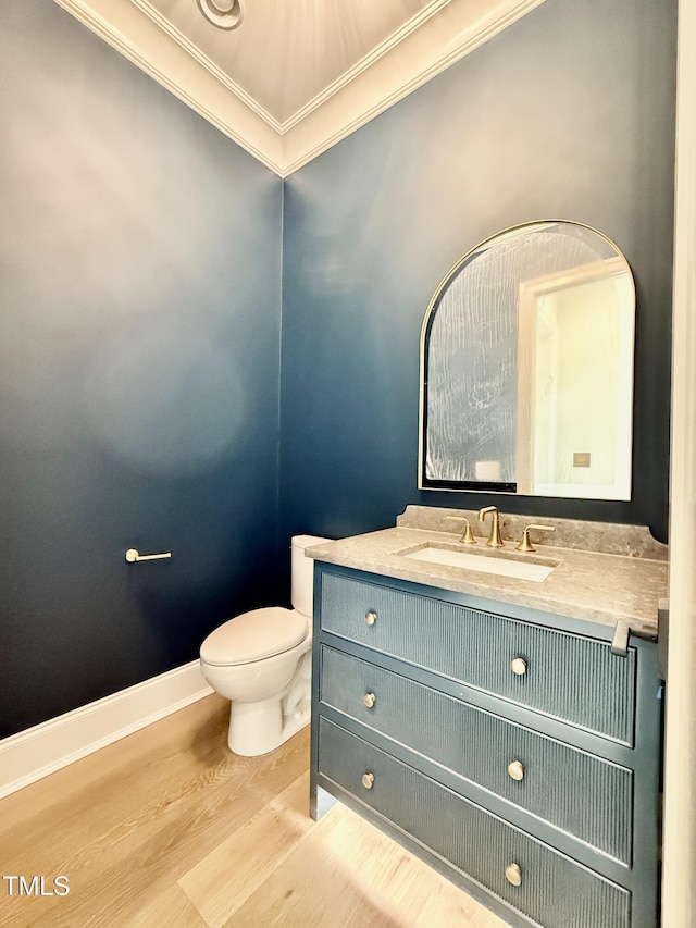 bathroom with ornamental molding, vanity, toilet, and hardwood / wood-style floors