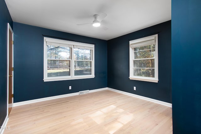 empty room featuring ceiling fan, a healthy amount of sunlight, and light hardwood / wood-style flooring