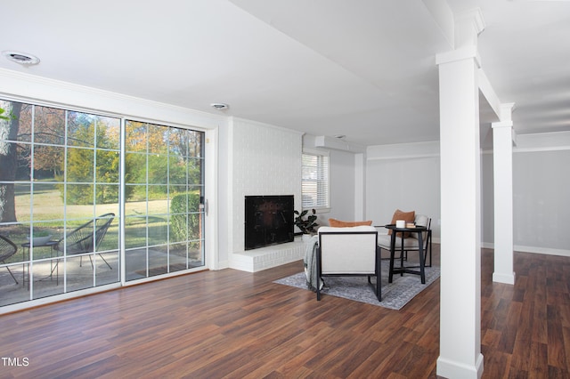 living room featuring a fireplace, dark wood-type flooring, a healthy amount of sunlight, and ornamental molding