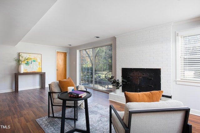 living room featuring ornamental molding, a brick fireplace, and dark wood-type flooring