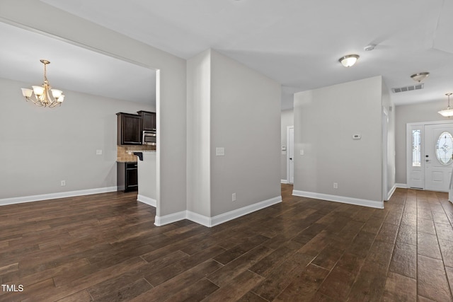 unfurnished living room with a chandelier and dark wood-type flooring