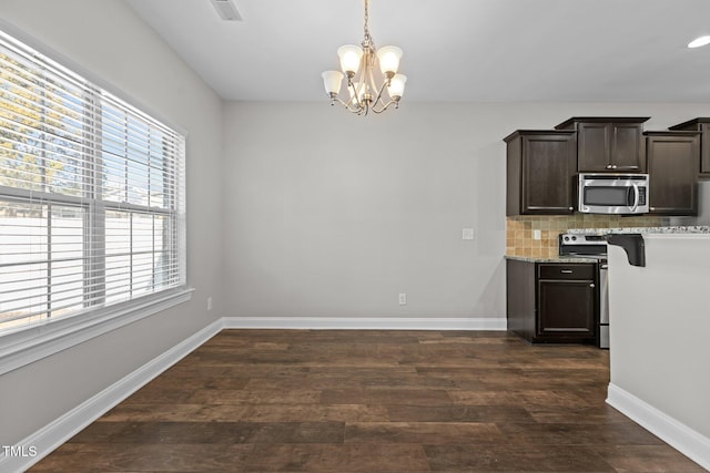 kitchen with decorative backsplash, appliances with stainless steel finishes, dark brown cabinetry, decorative light fixtures, and dark hardwood / wood-style floors