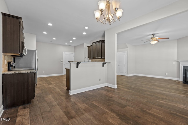 kitchen with a breakfast bar, dark hardwood / wood-style floors, light stone counters, and hanging light fixtures