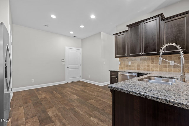 kitchen with light stone countertops, dark hardwood / wood-style flooring, dark brown cabinets, stainless steel appliances, and sink