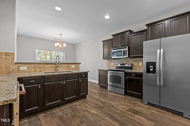 kitchen featuring sink, dark wood-type flooring, stainless steel appliances, a chandelier, and decorative backsplash