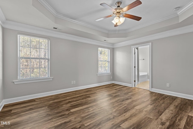 empty room featuring a tray ceiling, ceiling fan, dark hardwood / wood-style floors, and ornamental molding