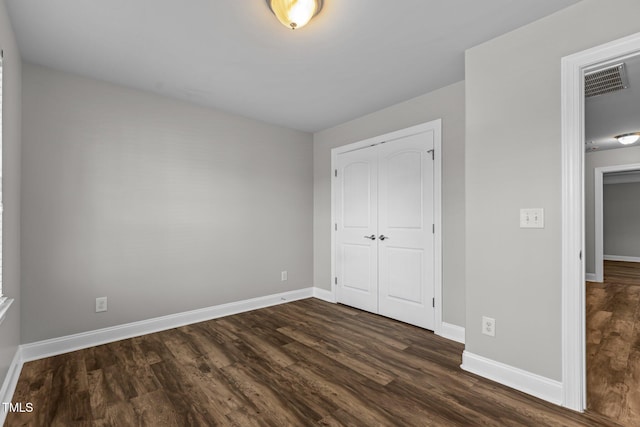 unfurnished bedroom featuring a closet and dark wood-type flooring