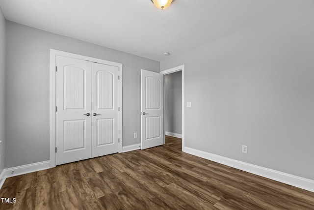 unfurnished bedroom with dark hardwood / wood-style flooring and a closet