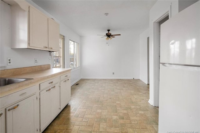 kitchen with white cabinets, white fridge, ceiling fan, and sink