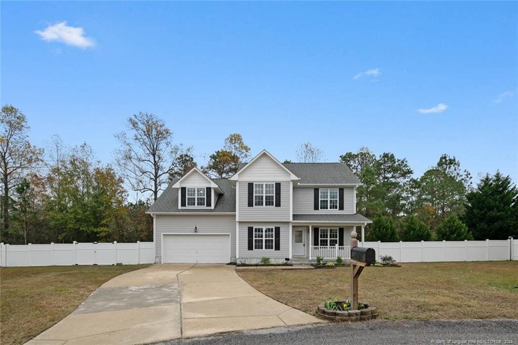 view of front of house with covered porch, a garage, and a front lawn