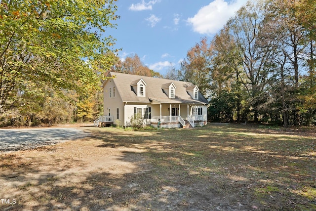 cape cod home featuring covered porch